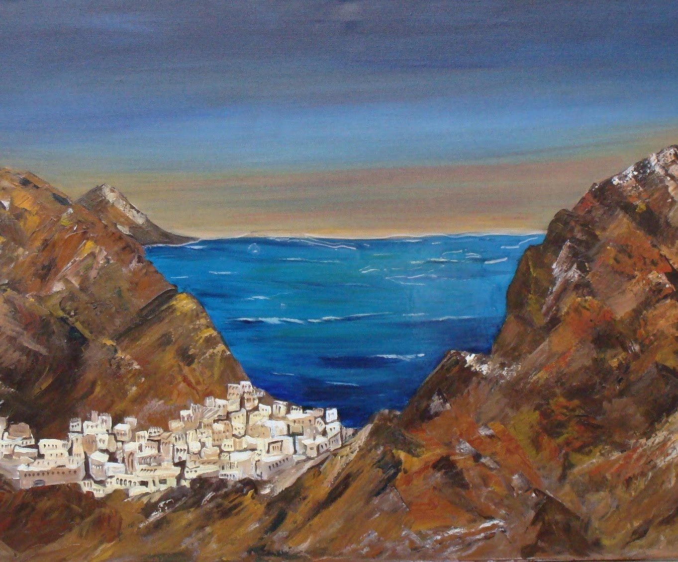 A white village between brown cliffs above a deep blue sea
