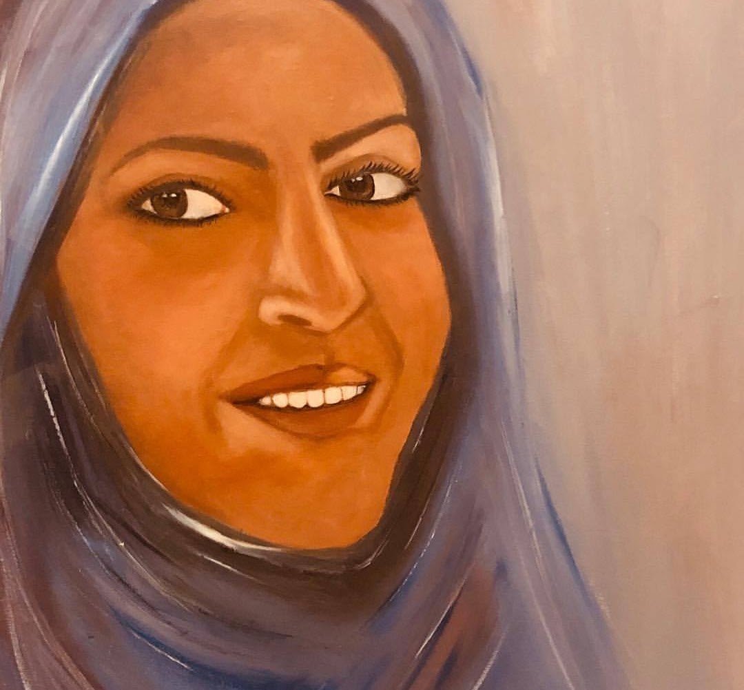 A smiling woman in a lilac headscarf