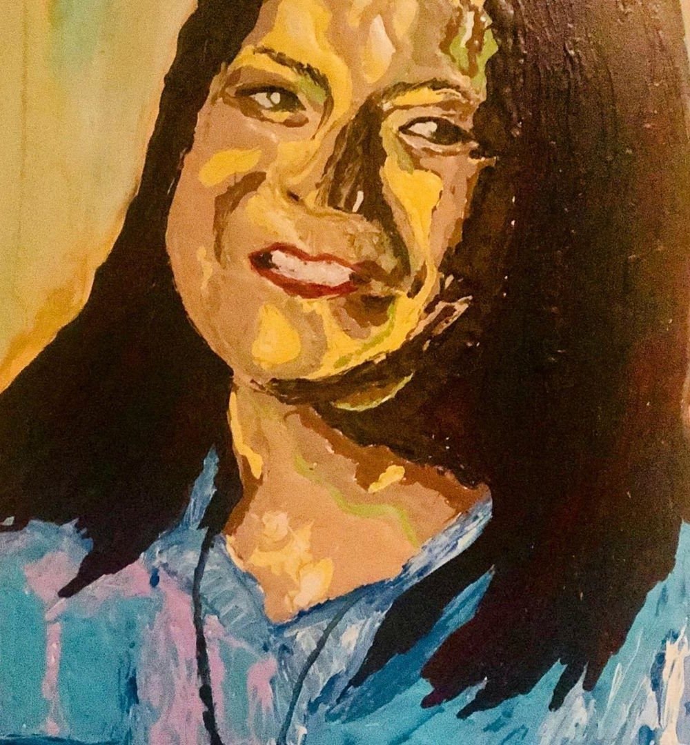 A woman with dark hair smiling, in warm yellows and blues